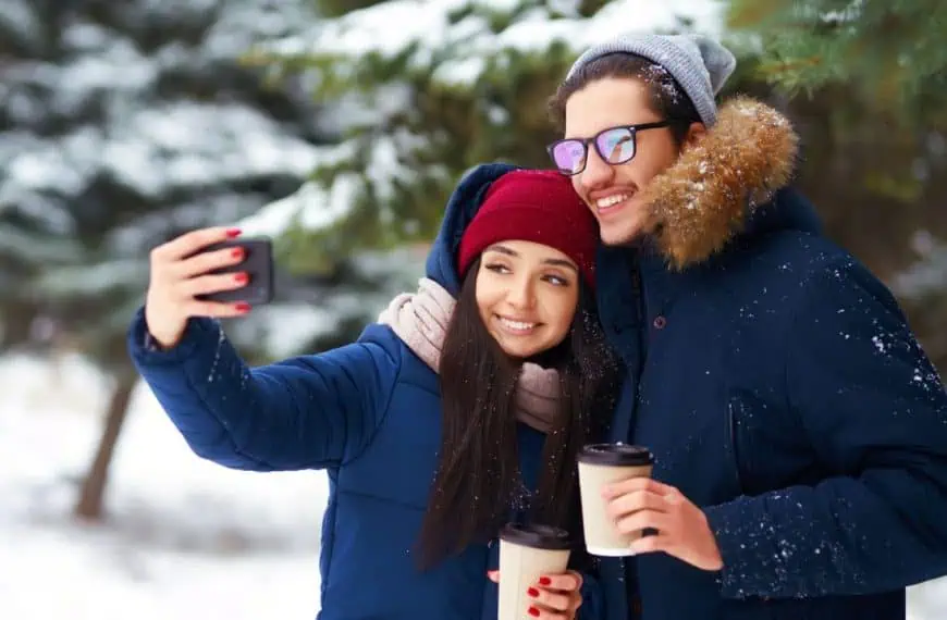 Couple man and woman in winter snow taking selfie