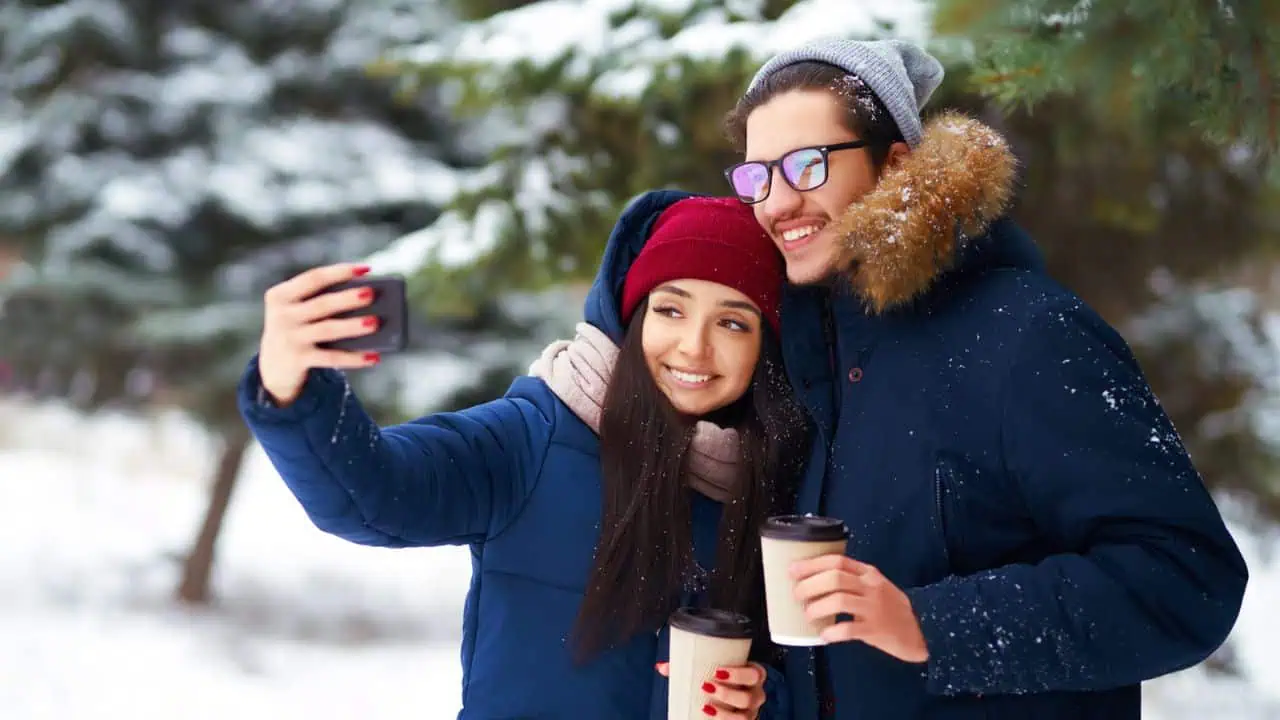 Couple man and woman in winter snow taking selfie