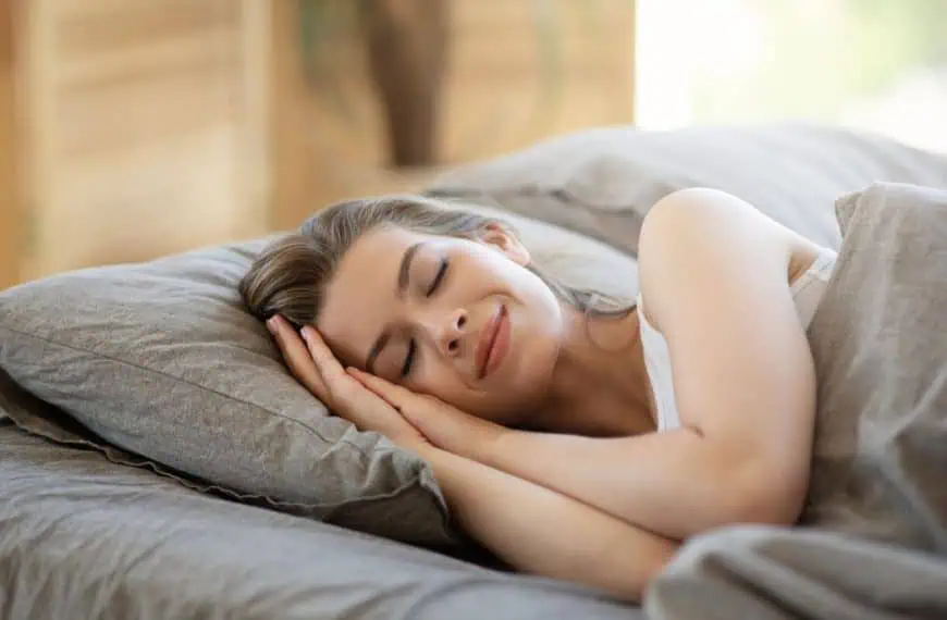 Young woman sleeping in hotel bed covered with blanket