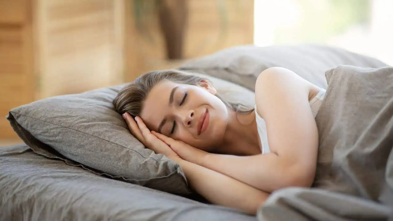 Young woman sleeping in hotel bed covered with blanket