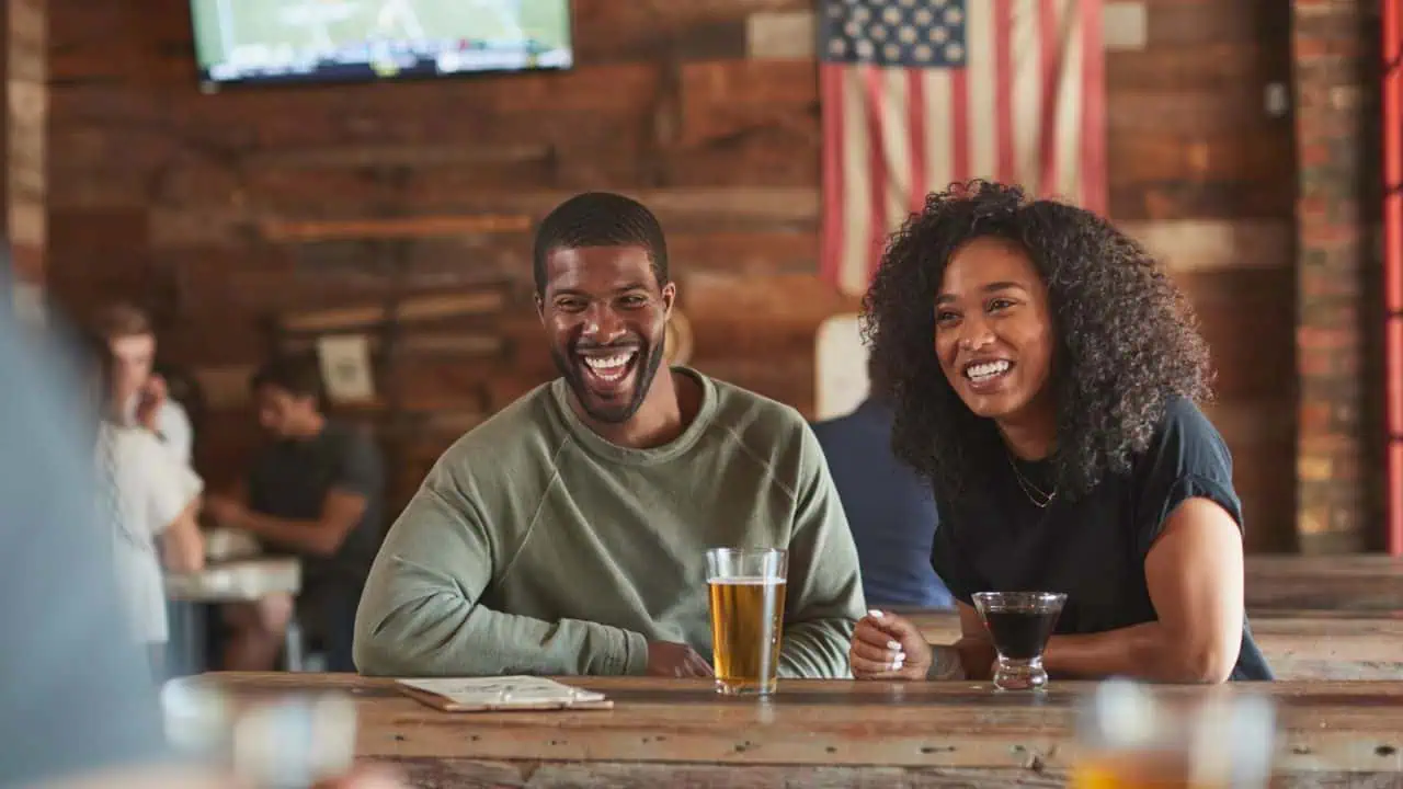 Young couple meeting in sports bar drinking